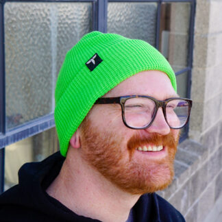 Male wearing neon green waffle texture beanie standing in front of a window.
